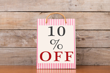 Shopping bags with inscription "10% OFF" on wooden background