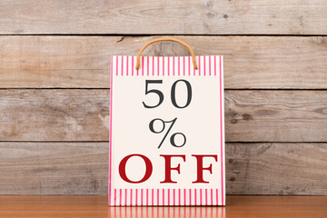 Shopping bags with inscription "50% OFF" on wooden background