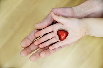 The small red heart is in the child's hand.