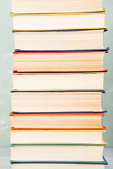 A stack of old colored books on shelf and green background