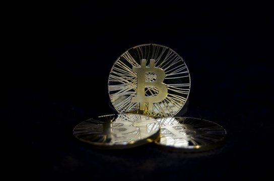 Three shiny bitcoin coins on black background