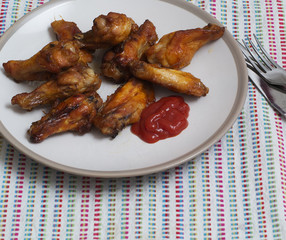 Fried chiken wings with ketchup on a plate.