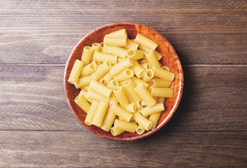 First plane of plate with macaroni on table of wood. Horizontal shoot.