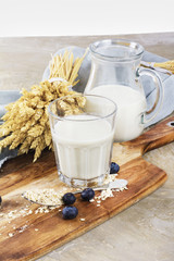Glass of ecological oat milk with berries on wooden desk