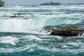 The bright blue water of Niagara Falls flows down the river and over the waterfall in spring