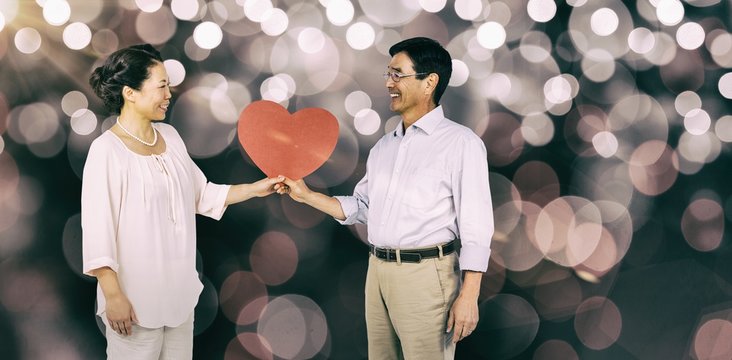 Composite image of older asian couple holding heart
