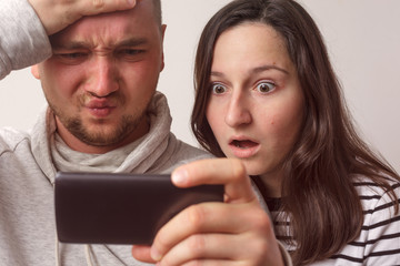 Couple of young people look at smartphone screen and see something