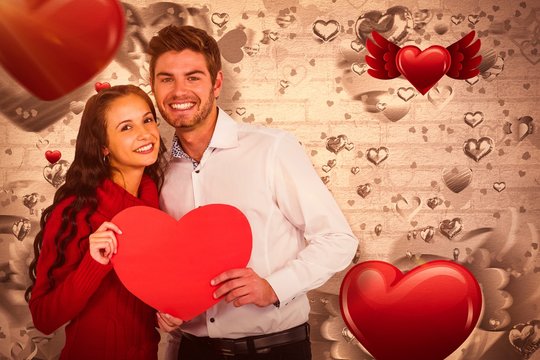 Composite image of happy couple holding paper heart 3d