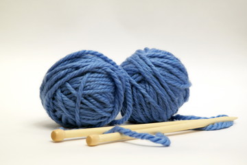 Fototapeta na wymiar Blue knitting wools and knitting needles on white background