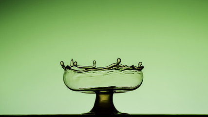 Water splashes sculpting a green cup looking like glass - liquid art