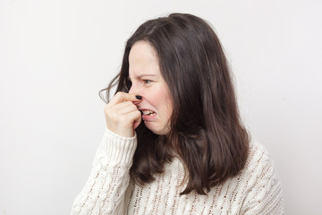 Girl with long hair plugs her nose because of disgusting smell