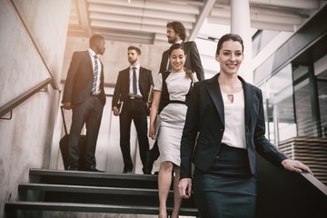 Confident businesswoman with colleagues climbing down stairs