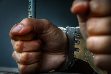 Human hand of prisoner on steel lattice close up.