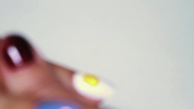 Manicure procedure female hand paints yellow emoticon on white finger nail polish, close up