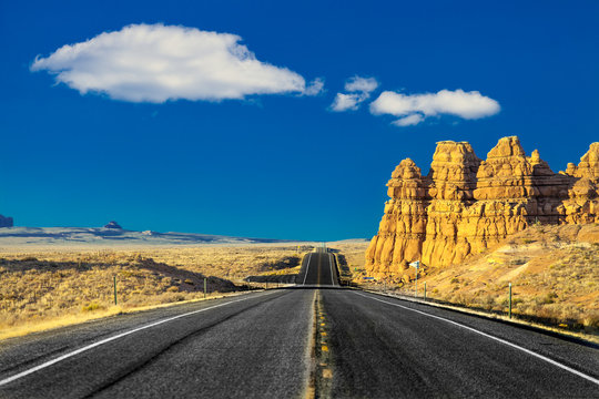 on the road in the desert of rocks and mountains in the United States in Utah with blue sky and clouds