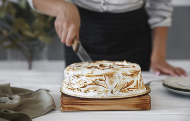 Woman cutting delicious cake on wooden board