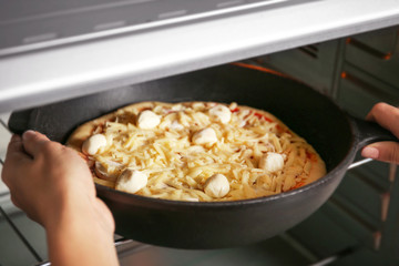 Woman putting pizza into oven