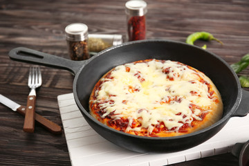 Freshly baked pizza in a pan on wooden background