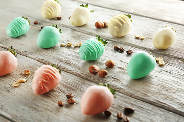 Strawberries covered with colorful chocolate icing on wooden background