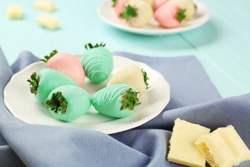 Plate of strawberries covered with colorful chocolate icing on napkin, closeup
