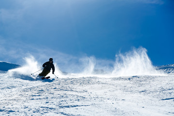 Skier dressed all in black moves quickly along a mountain on a clear blue day © Jeremy Francis