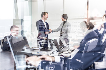 Sealing a deal. Business people shaking hands, finishing up meeting in corporate office....