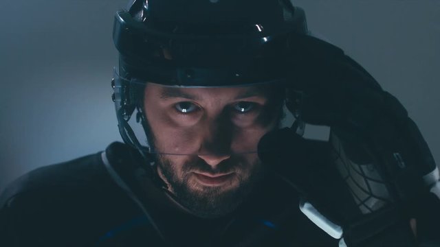 CU Portrait of Caucasian male ice hockey player in black uniform, looking into the camera. 4K UHD 60 FPS slow motion. RAW edited footage