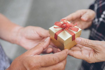 Senior man hand give a gift box to senior woman hand