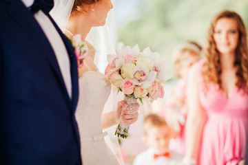 bride hold wedding bouquet of rose orchids and roses