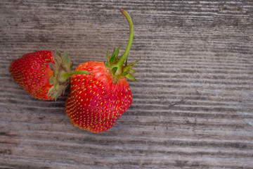 Two strawberry fruits on wooden background.
