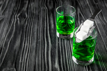 absinthe with sugar cubes and spoon on wooden background