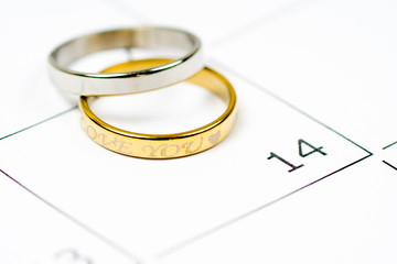 two rings golden and silver over 14 february calendar grid