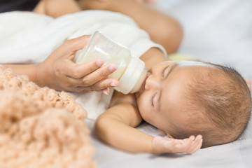 Obraz na płótnie Canvas hand of mother feeding milk from bottle and baby sleeping