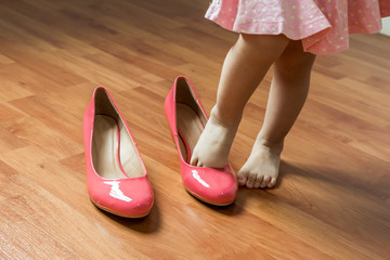 Baby girl wearing her mother's shoes