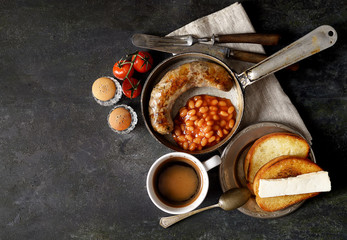 Breakfast in the pan, beans and sausages on a dark background