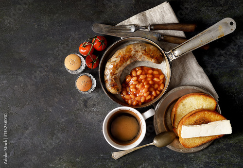 Breakfast in the pan, beans and sausages on a dark background