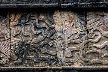 Ancient Mayan mural depicting a warrior holding a human head on the Platform of the Skulls, a.k.a. Tzompantli in Chichen Itza, Yucatan, Mexico
