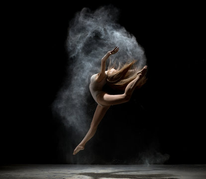Graceful girl dancing in white dust powder