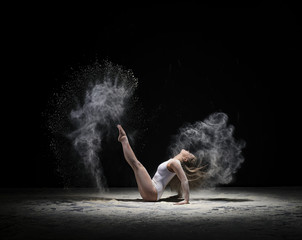 Obraz na płótnie Canvas Graceful gymnast exercising in cloud of white dust