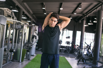 Fototapeta na wymiar Portrait of a man doing stretching exercises at gym.
