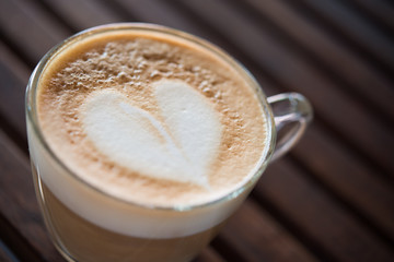 Close up of cappuccino cup with heart shaped milk pattern at caf
