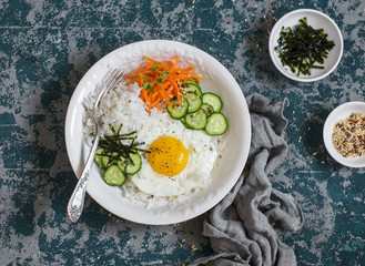 Rice with fried egg, pickled carrots, cucumber and seaweed. Healthy diet food concept. Top view