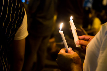 People holding candle vigil in darkness seeking hope, worship, prayer