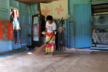 Indigenous Fijian woman cleans her home in Fiji - obrazy, fototapety, plakaty