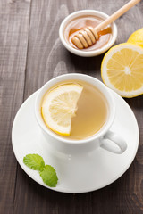 Cup of ginger tea with lemon and honey on wooden background