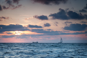 Ships at sea against the sky with clouds at sunset