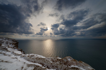 Seacoast in the snow, under heaven with clouds
