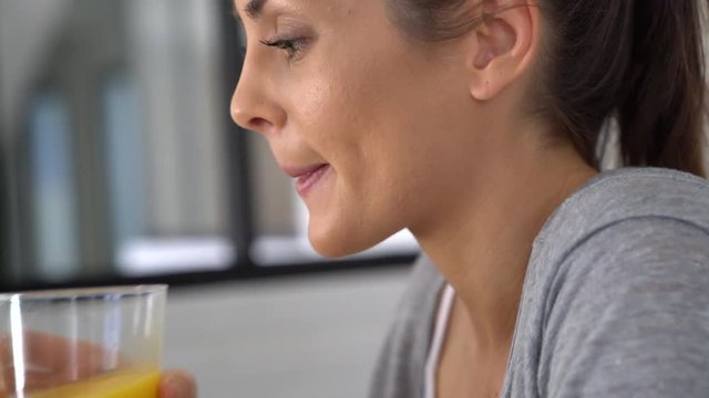 Closeup of young woman drinking orange juice