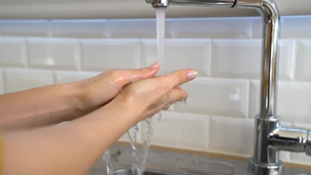 Woman washing her hands from faucet