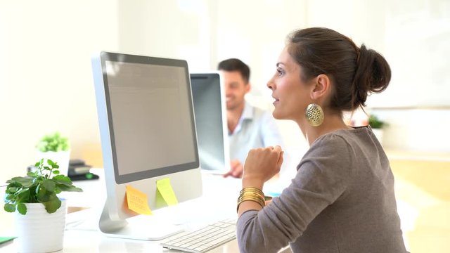 Cheerful startup girl working on desktop computer